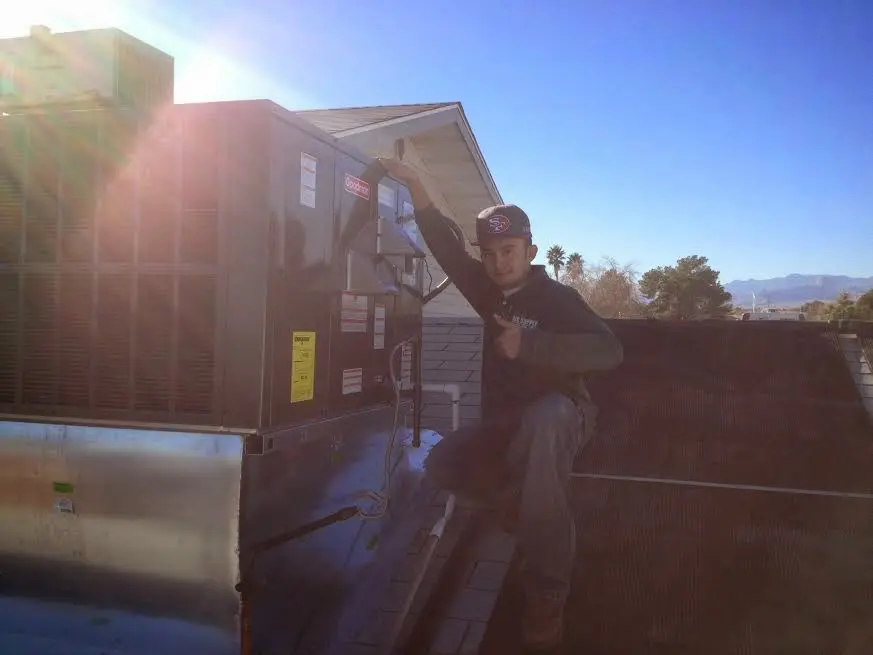 HVAC technician performing Air Duct Repair on a rooftop unit in Hutchinson