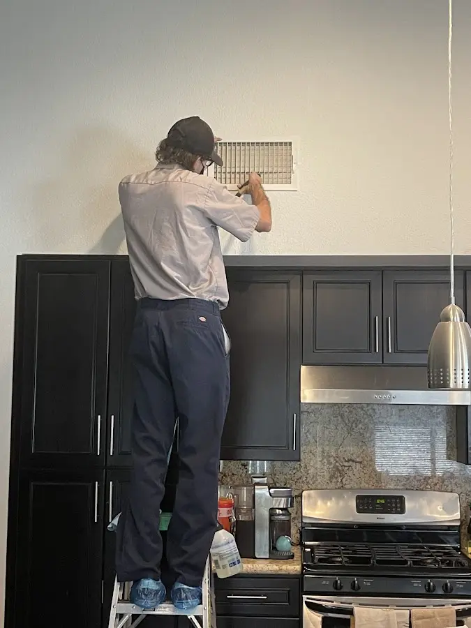 Technician inspecting an air vent during HVAC service in Hutchinson